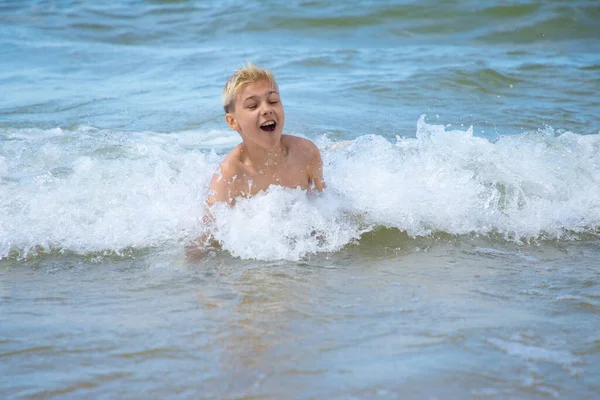 Toddler having fun in water with waves on the beach Stock Image