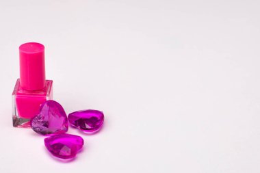 Beyaz arka planda mor renkli cam kalplerle pembe tırnak cilası. Boşluğu kopyala. Yüksek kalite fotoğraf