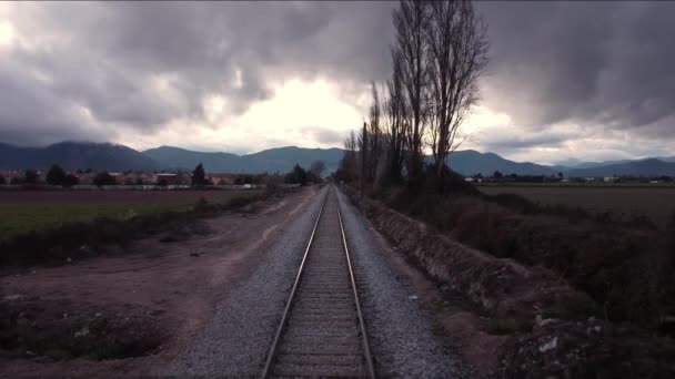 Tren hattından geriye doğru hareket ediyor. Hava bulutlu. Kenarlarda kırsal bölgeler. — Stok video