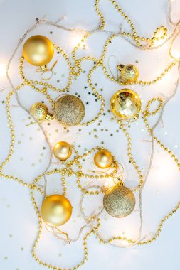 Noel kompozisyonu, altın noel süslemeleri ve sarı arka planda ışık ve metin için fotokopi alanı olan çelenkler. Görüntü. Düz yatıyordu. Kış, kartpostal şablonu.