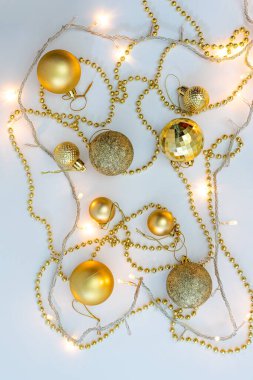 Noel kompozisyonu, altın noel süslemeleri ve sarı arka planda ışık ve metin için fotokopi alanı olan çelenkler. Görüntü. Düz yatıyordu. Kış, kartpostal şablonu.