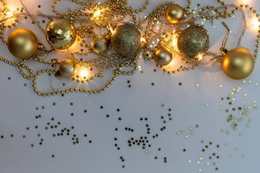 Noel kompozisyonu, altın noel süslemeleri ve sarı arka planda ışık ve metin için fotokopi alanı olan çelenkler. Görüntü. Düz yatıyordu. Kış, kartpostal şablonu.