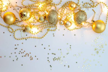 Noel kompozisyonu, altın noel süslemeleri ve sarı arka planda ışık ve metin için fotokopi alanı olan çelenkler. Görüntü. Düz yatıyordu. Kış, kartpostal şablonu.