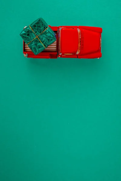 Coche Rojo Miniatura Parte Posterior Lleva Regalo Sobre Fondo Verde — Foto de Stock