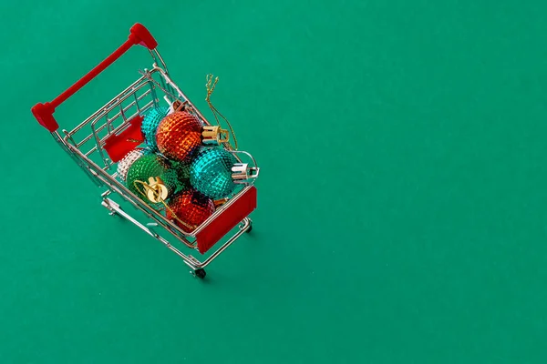 带有蓝绿色简单背景的圣诞球玩具的购物车 平躺在床上 省省吧 明信片模板 图库图片