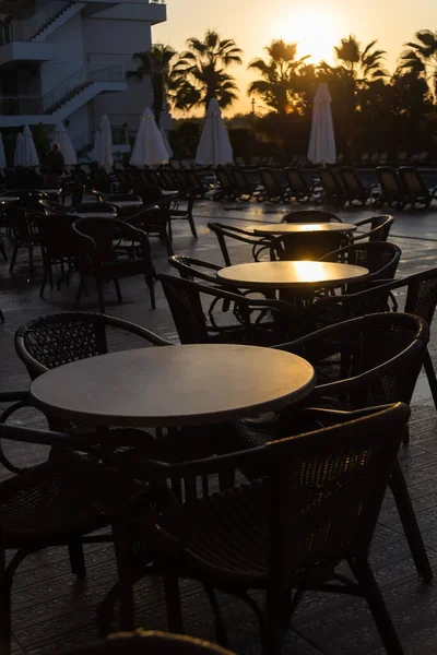 Mesas en un café de la calle turca en la luz de la mañana temprano contra el telón de fondo de las palmeras — Foto de Stock