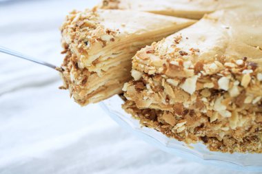 yuvarlak Napolyon pastası, karamel kremalı ve beyaz arka planda kesilmiş bir parça. Boşluğu kopyala.