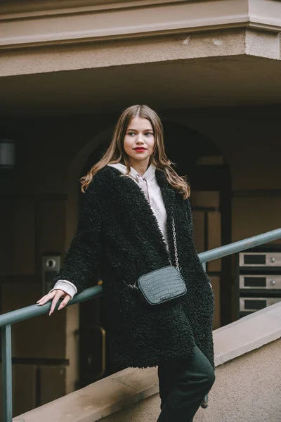 Photo en gros plan de jeune belle femme en manteau de fourrure noire, jeanse et chaussures posant dans la rue — Photo