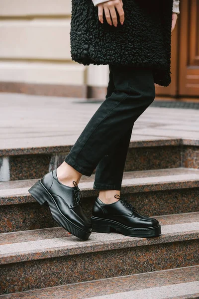 城市街道上穿着黑色皮大衣 牛仔裤和鞋子的年轻女子的时尚照片 — 图库照片