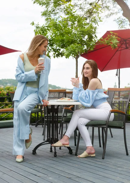 Две молодые подруги в кафе завтракают, обсуждают новости, смеются. женщины в кафе пьют коктейли. — стоковое фото