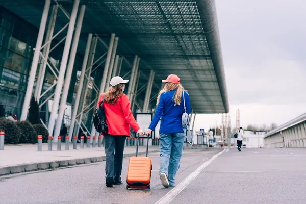 Dos chicas felices caminando cerca del aeropuerto, con equipaje. Viajes aéreos, vacaciones de verano —  Fotos de Stock