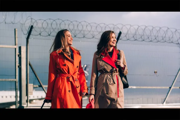 Havaalanının yakınında bavullarıyla yürüyen iki mutlu kız. Hava yolculuğu, yaz tatili. — Stok fotoğraf