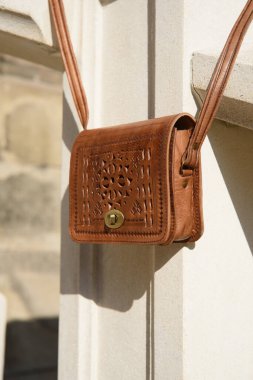 Küçük sarı kadın deri çantasına oyulmuş desenler.