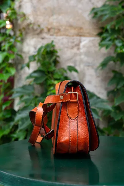 Small orange womens leather bag on a green table — Stock Photo, Image