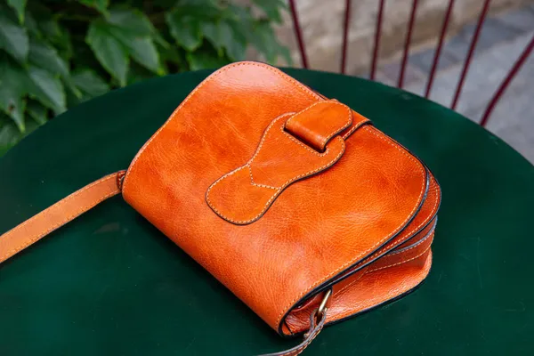 Маленькая оранжевая женская кожаная сумка на зеленом столе — стоковое фото
