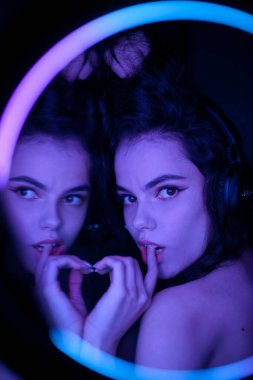 Kablosuz kulaklıklı, halka efektli genç bir kadının duygusal stüdyo portresi. Yuvarlak LED Çember Lamba.