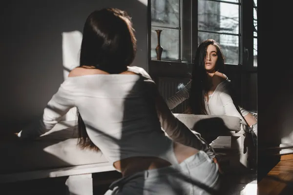 Retrato de hermosa mujer gentil en un traje de cuerpo blanco posando bajo el sol. Pelo largo negro. sensualidad y ternura — Foto de Stock