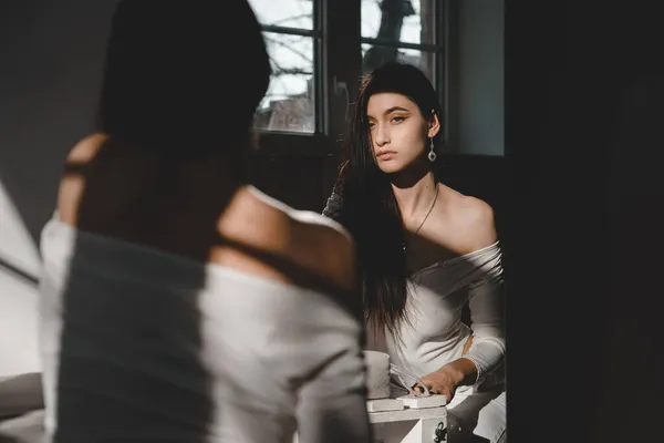 Portret van een mooie zachte vrouw in een wit bodysuit poserend in de zon. Zwart lang haar. sensualiteit en tederheid — Stockfoto