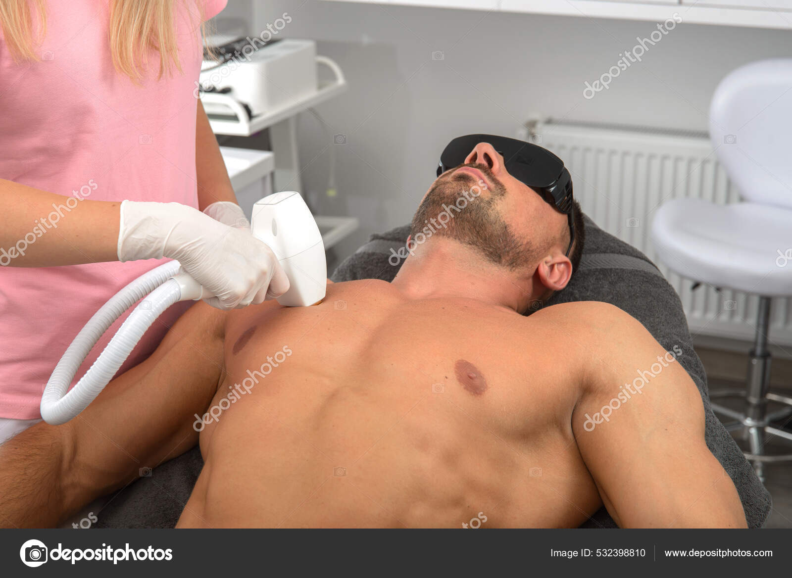 Dermatólogo en gafas realiza la depilación láser en el pecho del