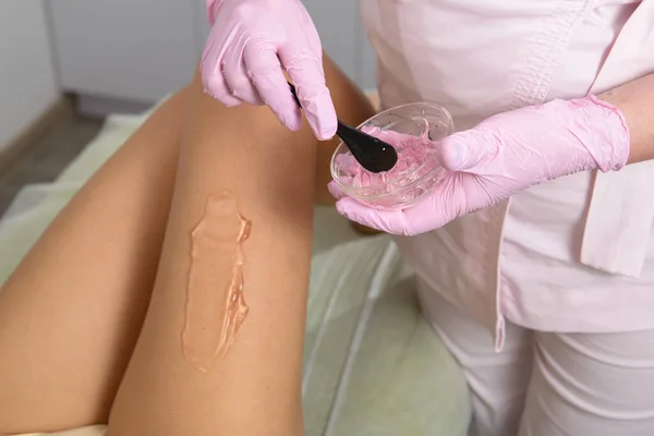 在医疗诊所，美容师在一名妇女的腿上涂上接触凝胶，以进行激光脱毛。靠近点 — 图库照片