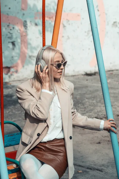 Portrait de femme blonde dans un casque écoutant de la musique avec des lunettes de soleil. Hipster fashion model porter des écouteurs sans fil élégants profiter d'écouter une nouvelle musique cool. — Photo