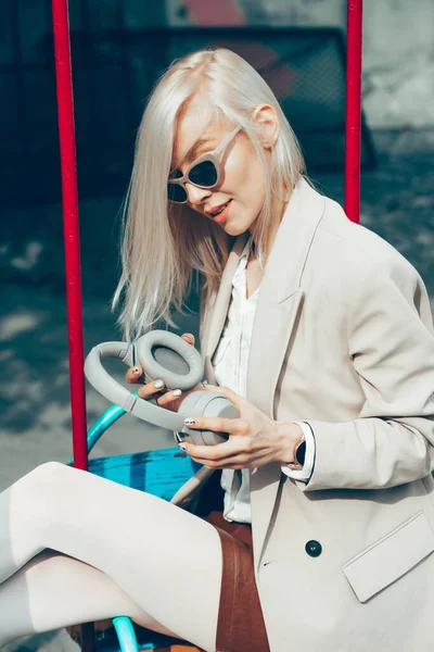 Retrato de mujer rubia con auriculares en las manos. Hipster modelo de moda llevar elegantes auriculares inalámbricos disfrutar escuchar nueva música fresca. — Foto de Stock
