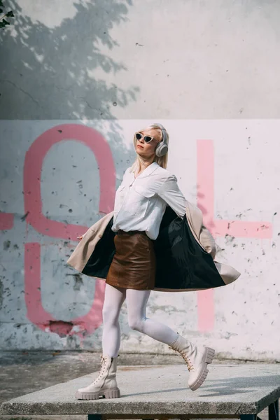 Retrato de mujer rubia en auriculares y gafas de sol. Hipster modelo de moda llevar elegantes auriculares inalámbricos disfrutar escuchar nueva música fresca. — Foto de Stock