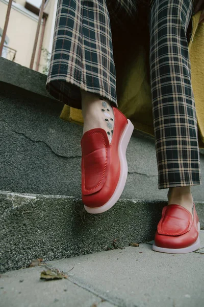 Женские ноги в клетчатых брюках и красных туфлях — стоковое фото
