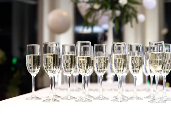 Hodně skleniček na víno se šampaňským nebo bílým vínem. . Hodně sklenic se šampaňským během párty. selektivní zaměření — Stock fotografie