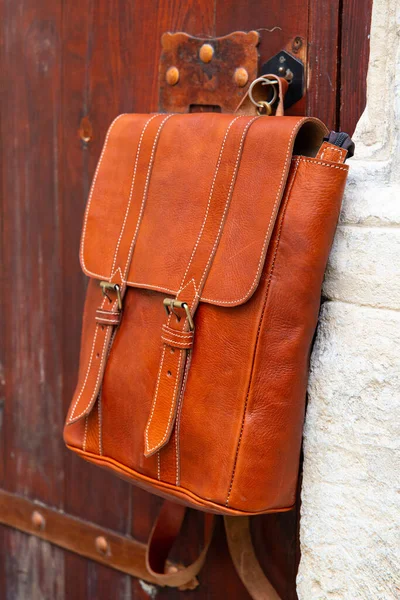 Stylish leather backpack on a rustic wooden door — Stock Photo, Image
