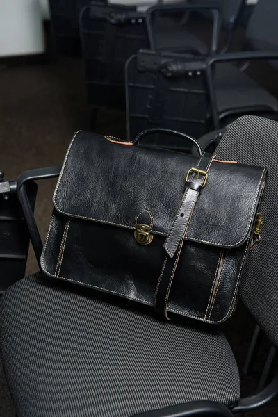 Black leather briefcase with antique and retro look for man on a office chair. photo taken in a conference hall — Stock Photo, Image