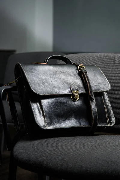 Black leather briefcase with antique and retro look for man on a office chair. photo taken in a conference hall — Stock Photo, Image