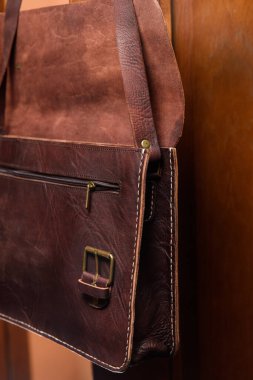 Antika ve retro görünümlü kahverengi deri evrak çantasını aç ve sandalyede bir adam ara. Otel odası fotoğrafı.