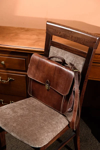 Brown leather briefcase with antique and retro look for man on a chair. Hotel room photo — Stock Photo, Image