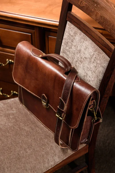 Brown leather briefcase with antique and retro look for man on a chair. Hotel room photo — Stock Photo, Image
