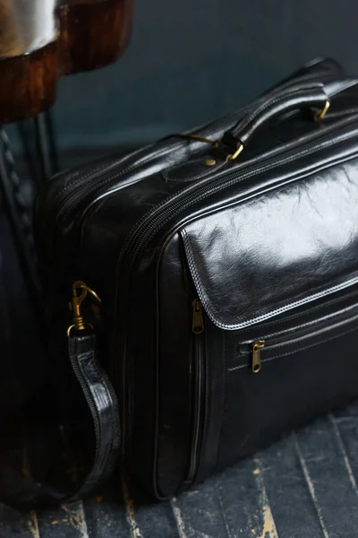 Кожа черная дорожная сумка, на черном деревянном полу — стоковое фото