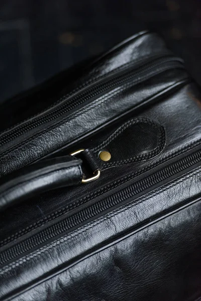 Leather black travel bag, on a black wooden floor — Stock Photo, Image