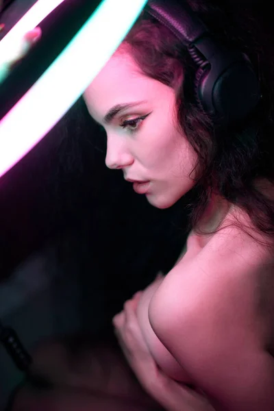 Emocionální studiový portrét mladé ženy v bezdrátových sluchátkách s efektem zvonění. Kulatá LED kruhová svítilna. — Stock fotografie