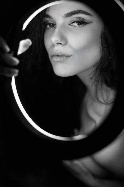 Retrato de estúdio emocional de uma jovem mulher em fones de ouvido sem fio com efeito flash de anel. Lâmpada de círculo LED redonda. — Fotografia de Stock