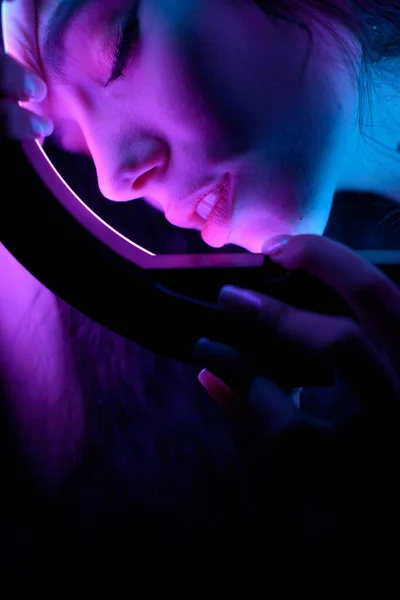 Emotioneel studioportret van een jonge vrouw in een draadloze hoofdtelefoon met ringflitseffect. Ronde LED Cirkellamp. — Stockfoto