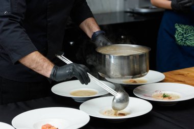 Şef somon, peynir ve beyaz çorba kaselerinde otlu balık kreması çorbası pişiriyor.