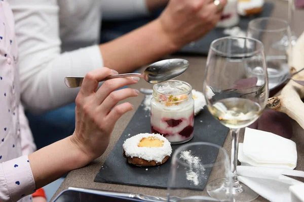 Woman eats dessert in a glass cup, with Jello, yogurt and topping served in a restaurant. Mini desserts