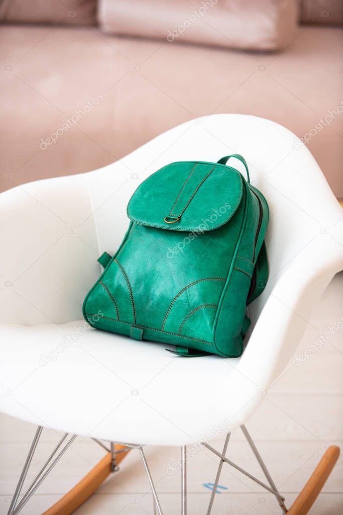 A green leather modern backpack on a white chair