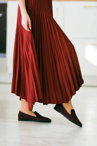 Foto van vrouwenbenen in een stijlvolle suède bordeauxrode loafers. vrouw draagt rode rok. — Stockfoto