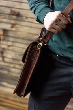 Erkeğin elinde kahverengi deri çantanın yakın plan fotoğrafı.