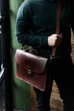 Erkeğin elinde kahverengi deri çantanın yakın plan fotoğrafı.