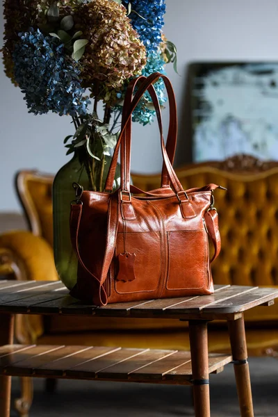 Close-up photo of orange leather bag on a wooden table — Stock Photo, Image