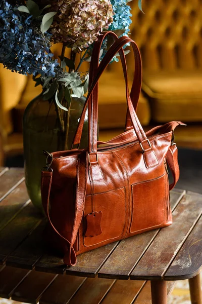 Close-up photo of orange leather bag on a wooden table — Stock Photo, Image