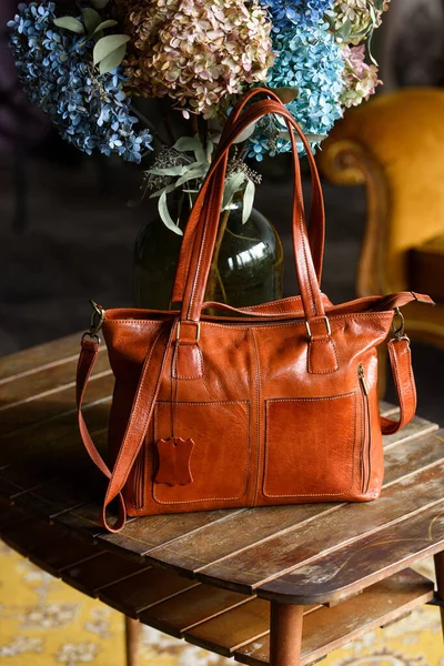 Close-up photo of orange leather bag on a wooden table — Stock Photo, Image