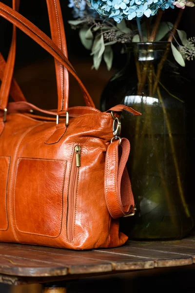 Close-up photo of orange leather bag on a wooden table — Stock Photo, Image